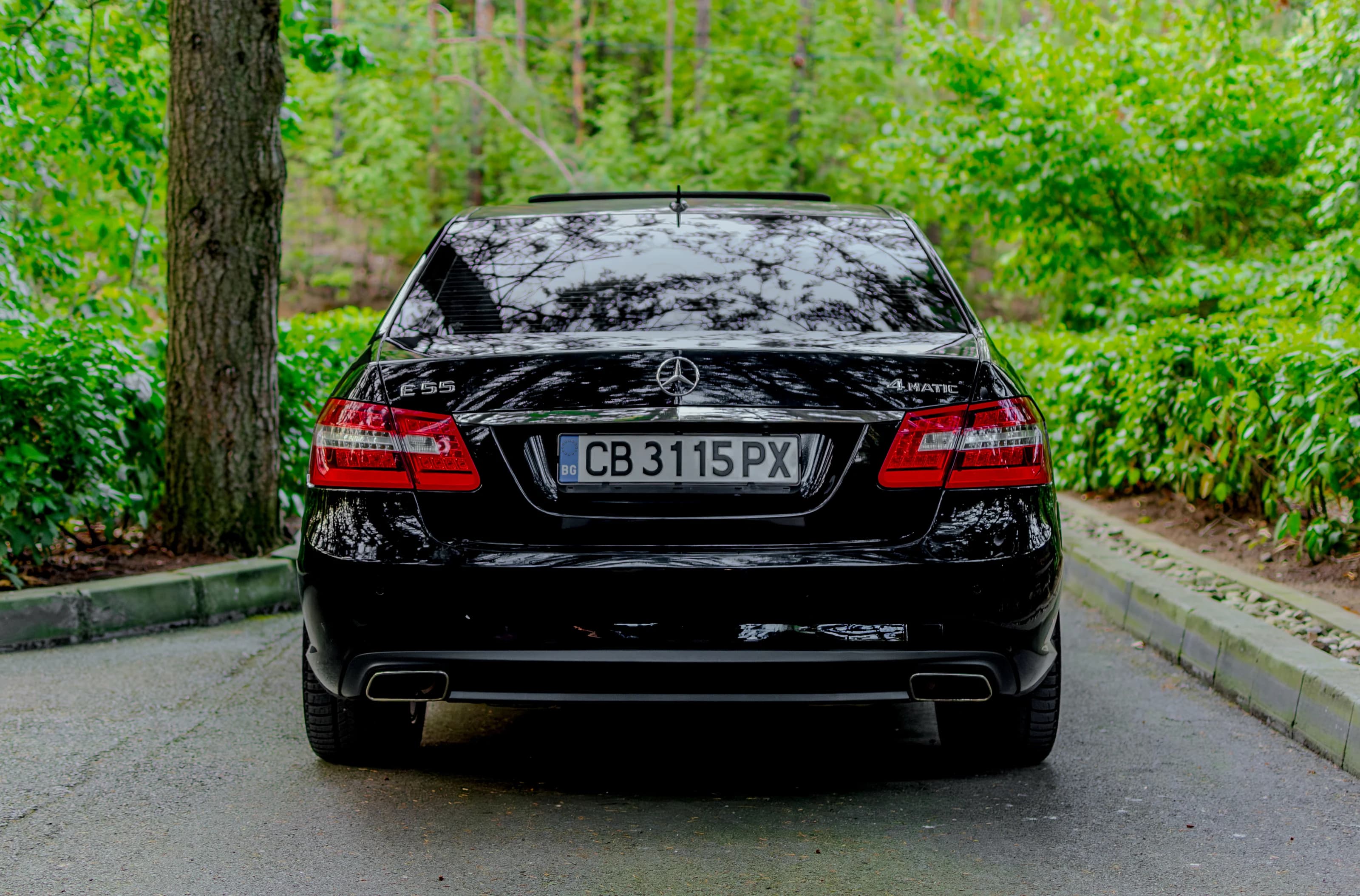 Черен Mercedes E55, заснет фронтално сред зеленина