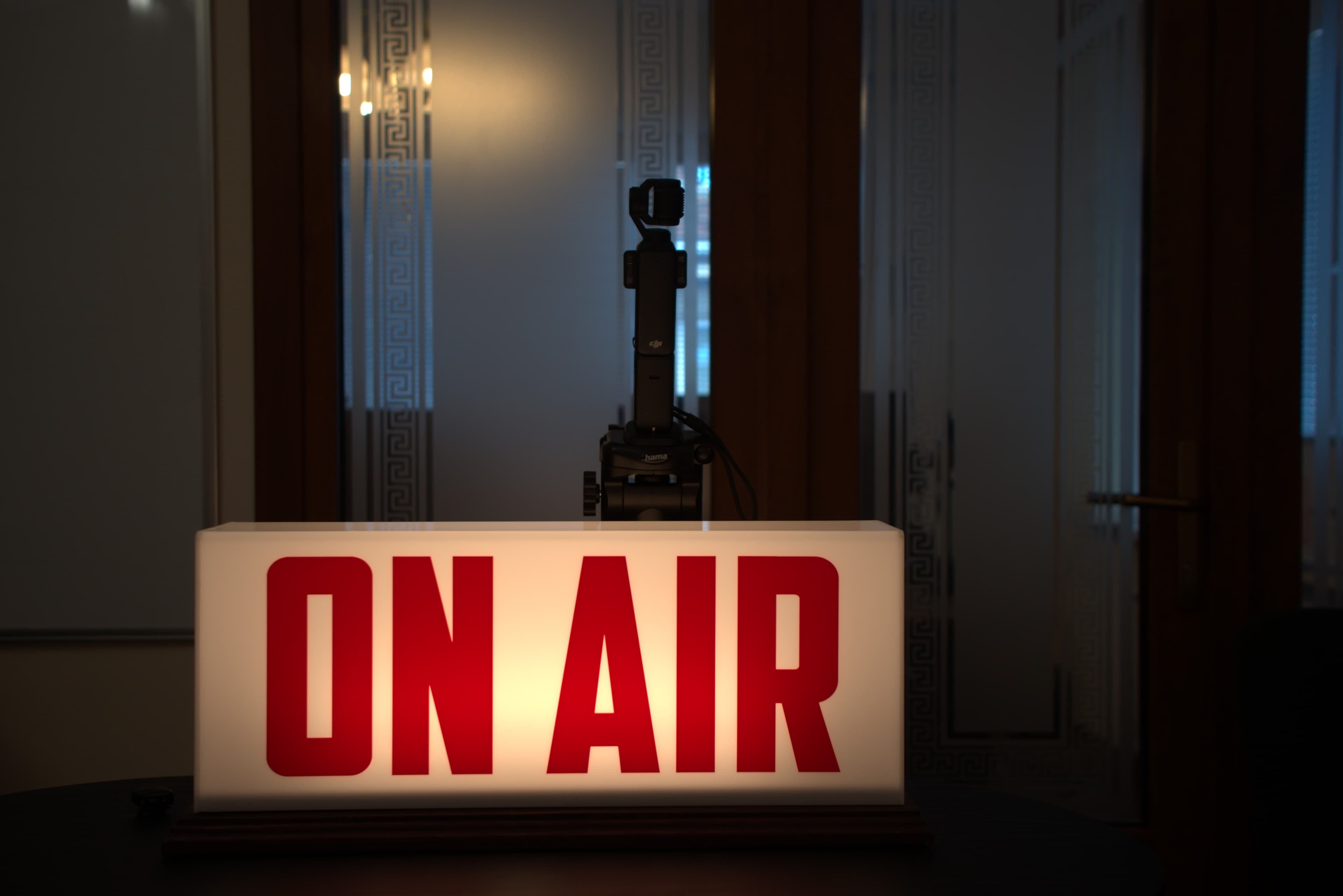 Осветена табела ON AIR пред камера в тъмно студийно пространство